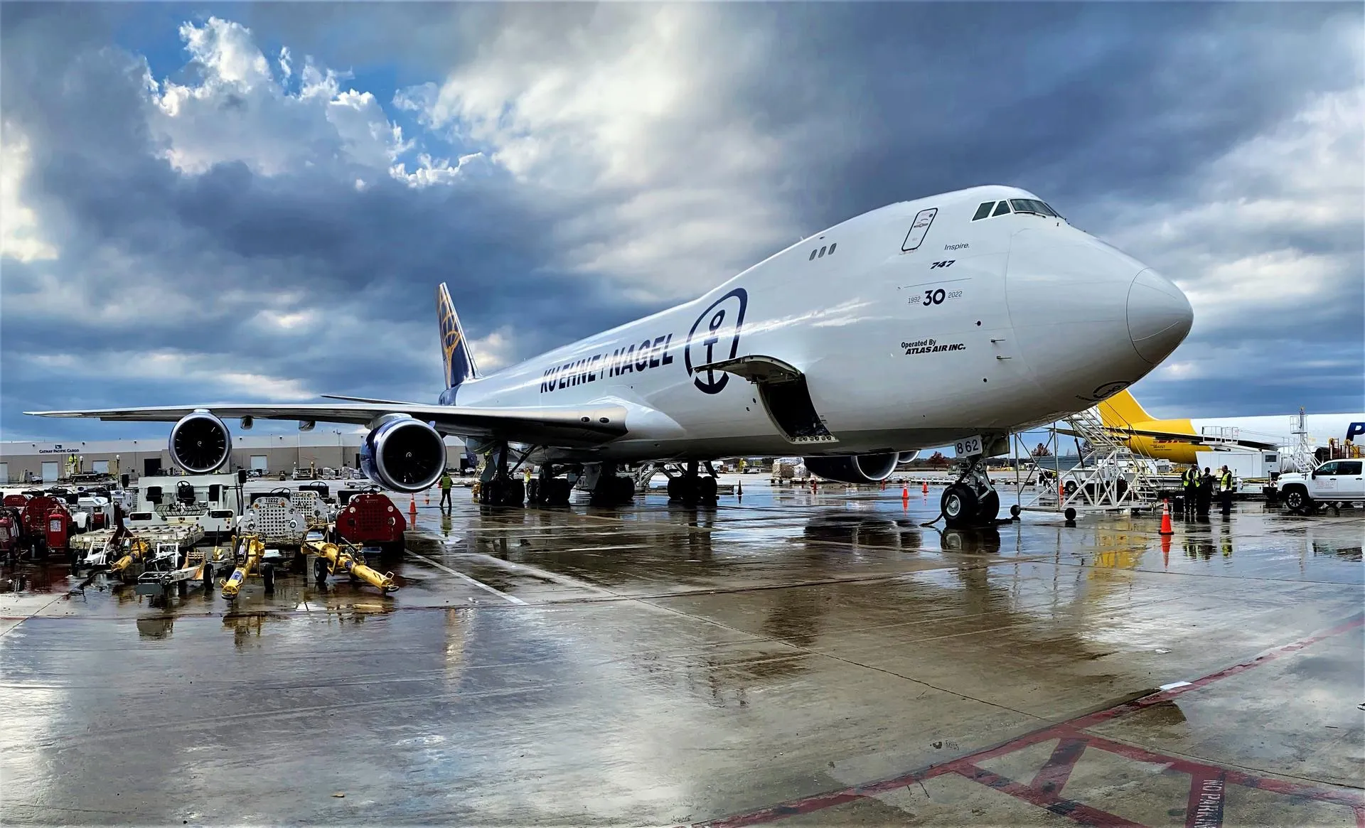 A Kuehne+Nagel Boeing 747 is being loaded on a rainy day at an airfield