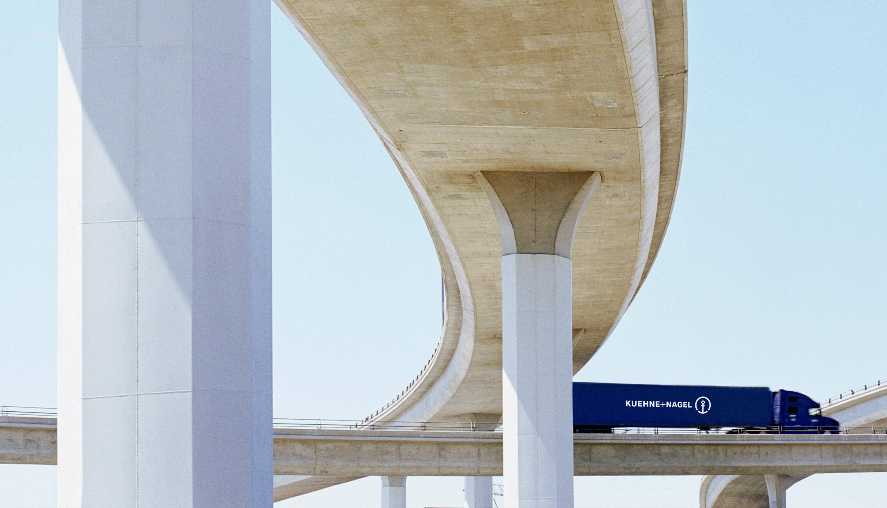 A blue KN truck passes under the bridge